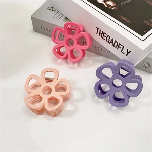 Detailed macro view of large hollow flower hair claws in matte pastel pink and apricot colors