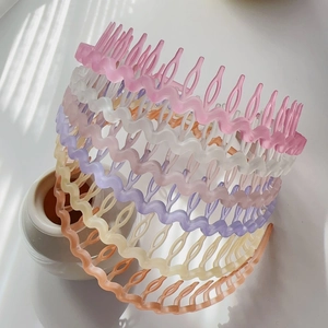 Detail showing colorful wavy plastic headbands with comb teeth on a white vase