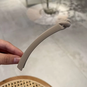 Close-up of matte beige banana hair clip with minimalist twist design and sand finish