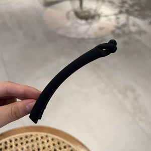 Detail of matte black banana hair clip with minimalist knot design for women