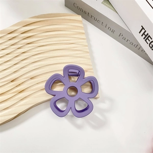 Detailed macro view of a purple hollow flower hair claw clip on a textured wood surface