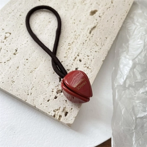 Détail du charme tulipe rouge avec texte France Handmade sur un élastique à cheveux marron