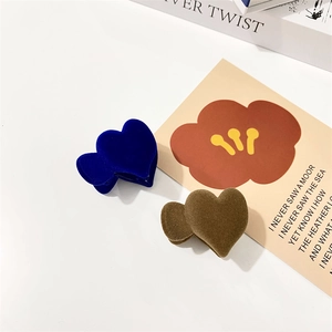 Detail of heart-shaped flocked hair claws in royal blue and coffee brown on minimalist white background