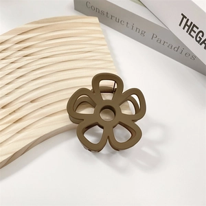 Detailed close-up of matte brown hollow flower hair claw clip on wooden background