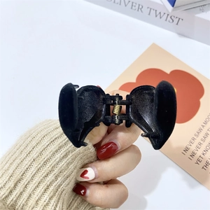 Detail of hand holding a black flocked heart claw clip with golden metal spring