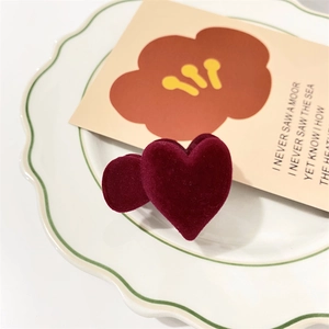 Macro shot of deep red velvet heart hair clips displayed on a white ceramic plate