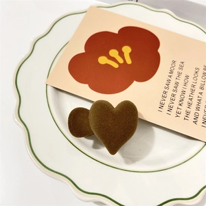 Macro detail of coffee brown flocked heart hair clips on a vintage ceramic plate