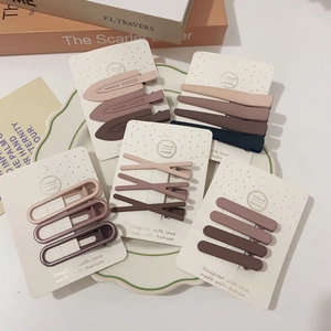 Detailed view of handmade matte hair clips in earthy tones on a white display card