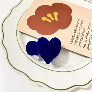 Close-up of deep blue velvet flocking heart hair clips on a white ceramic plate