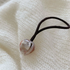 Détail de l'élastique à cheveux tulipe avec pendentif fleur sur fond en maille blanche
