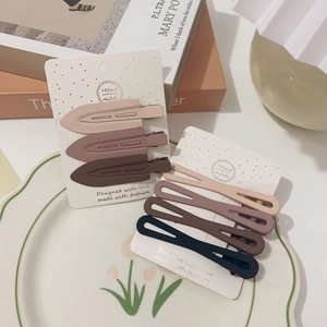 Detail of 7 matte finish metal hair clips in beige, purple, and brown on a display card