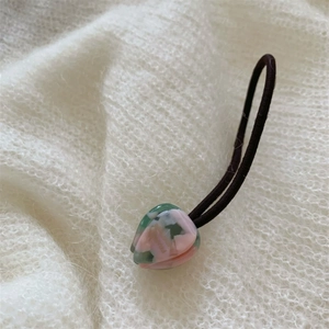 Détail d'un chouchou avec perle de cœur marbrée sur fond de tissu en maille blanc