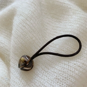 Détail de l'élastique à cheveux tulipe avec perle acrylique en forme de cœur sur tricot blanc