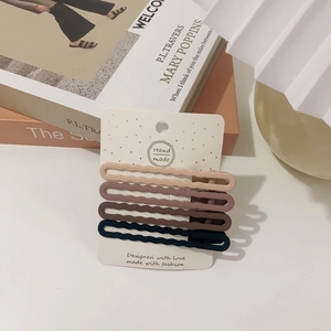 Close-up of four matte wavy hair clips in pastel colors on a handmade display card