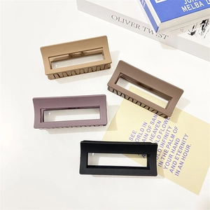 Detailed close-up of four matte square hair claws in earth tones and black on a desk