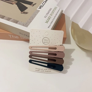 Set of four matte geometric hair clips in beige, pink, brown, and navy blue on card