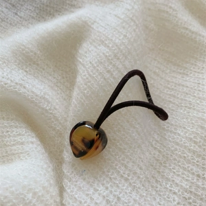 Détail d'un pendentif cœur en écaille avec texte doré France Handmade sur un chouchou noir
