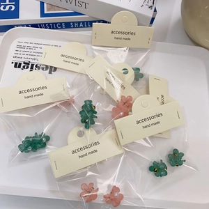 Pinces à cheveux camélia en vert émeraude et rose corail sur un plateau élégant