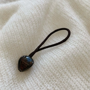 Détail d'une perle ambrée gravée France Handmade sur un élastique à cheveux noir