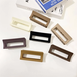Flat lay of large rectangular matte hair claws in seven earthy neutral colors on white back