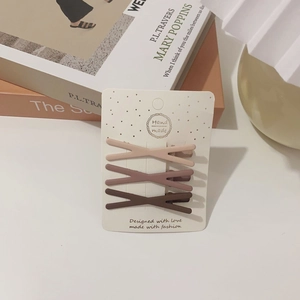 Three-piece earth tone matte X-shaped hair clips displayed on a white aesthetic card