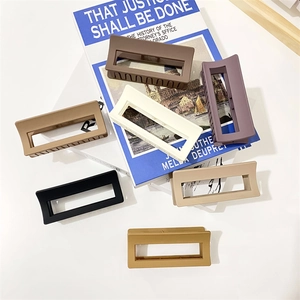Close-up of matte rectangular hair claws in various earthy tones on a white surface