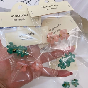 Détail de pinces à cheveux fleur de camélia roses et vertes avec perles en emballage