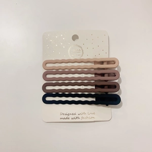 Close-up of four matte wavy hairpins in morandi colors on a white display card