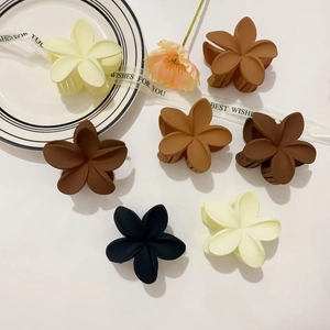 Set de pinzas para el pelo con flores mate en tonos tierra sobre una bandeja blanca