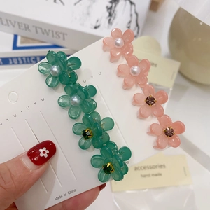 Vue détaillée de petites pinces à cheveux camélia avec perles et strass sur carte
