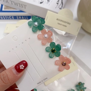 Détail de petites pinces à cheveux camélia en résine avec perles et strass brillants