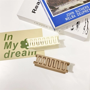 Set of matte resin hair claws in cream and light brown displayed on a stack of books
