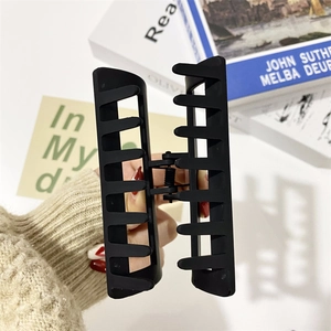 Matte black rectangular large hair claw clip for thick hair shown in hand closeup