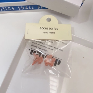 Gros plan de petites barrettes camélia rose avec perles et étiquettes fait main