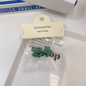 Détail de boucles d'oreilles fleur verte avec cœur doré sur carte faite main