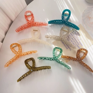 Detail of colorful geometric resin hair claws with golden springs and matte finish