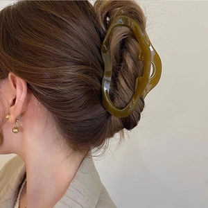 Nahaufnahme der olivgrünen Haarklammer in Wellenform für einen eleganten Dutt
