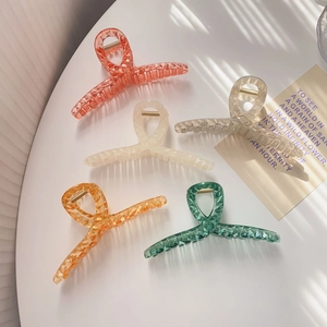 Detailed view of large acrylic hair claws with geometric crystal cutting in five colors