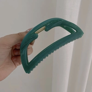 Dettaglio di una grande pinza per capelli in acrilico verde scuro con chiusura a molla