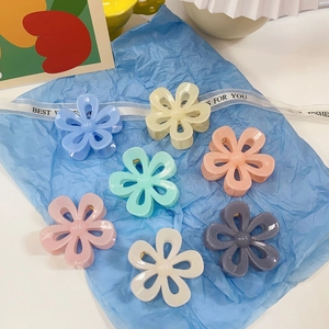 Flat lay of seven colorful floral hair claws in pastel tones on blue background