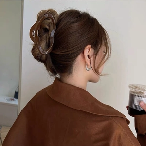 Detailaufnahme einer großen, glänzenden braunen Haarklammer im minimalistischen Stil