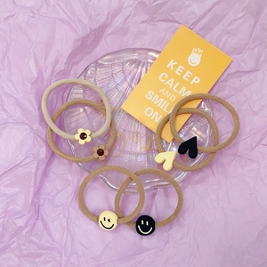 Detailed close-up of six elastic hair ties with floral, heart, and smiley face resin charms