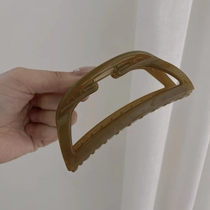 Dettaglio molletta per capelli in acrilico ambra traslucido con design geometrico