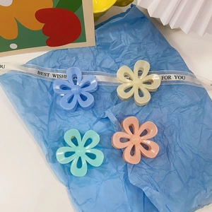 Close-up of four matte jelly flower hair claws in pastel blue, yellow, green, and pink colors