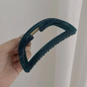 Dettaglio della molletta per capelli in marmo verde scuro con molla dorata e forma a D