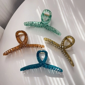Detailed macro view of four translucent geometric hair claws with elegant striped shadows