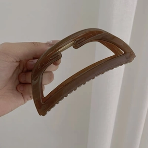 Dettaglio della molletta per capelli in acrilico marrone scuro con molla in metallo