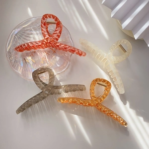 Detail of four colorful acrylic shark hair claws with geometric diamond texture and metal spring