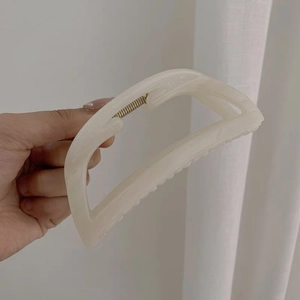 Dettaglio della pinza per capelli in acrilico marmorizzato crema con molla dorata