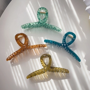 Detail of four colorful translucent acrylic hair claws with geometric faceted texture